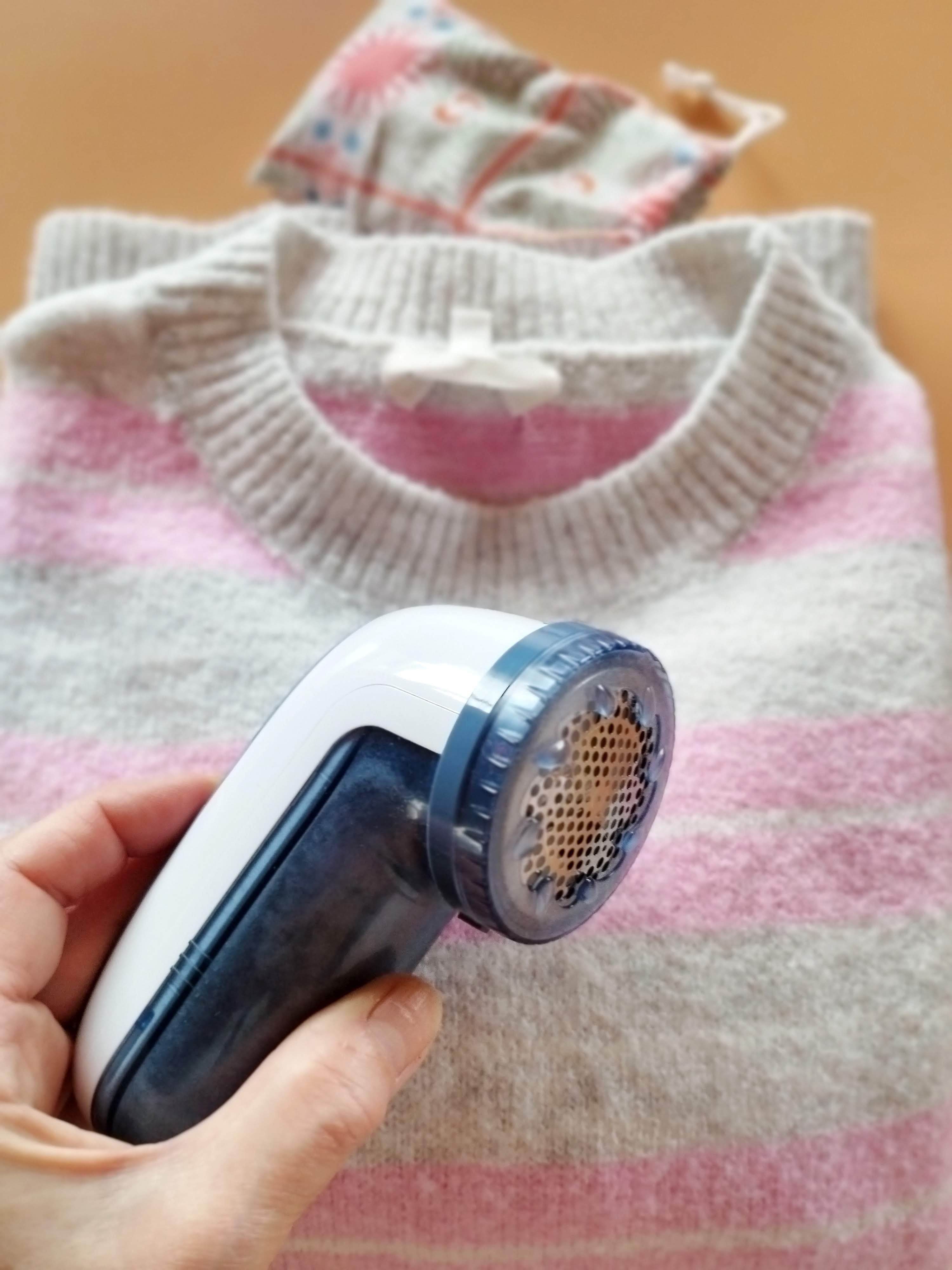 un beau pull avec en gros plan un rasoir électrique anti-bouloches pour un linge impeccable et son entretien