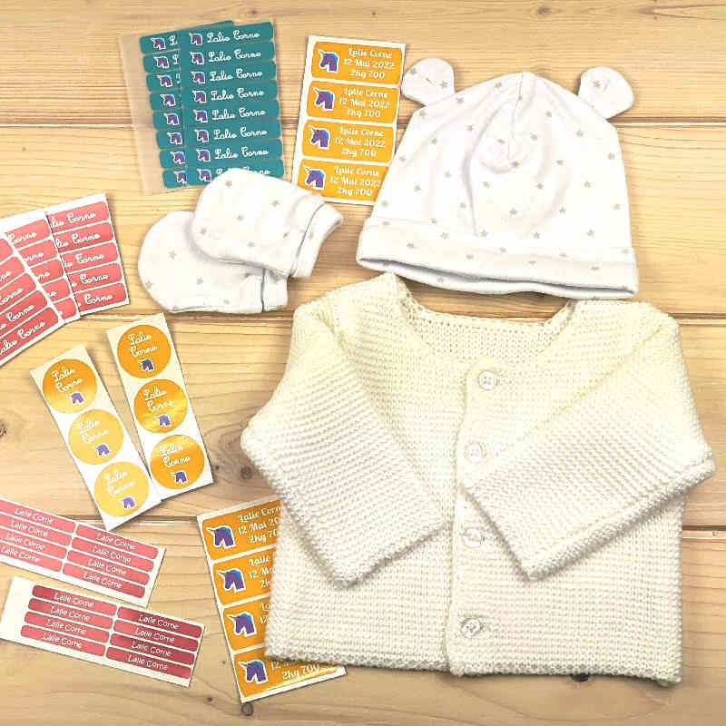 un pack d'étiquettes vêtements et objets thermocollantes et autocollantes assorties Marcabi pour marquer les affaires de bébé et enfant avec un gilet tricoté, un bonnet et des objets